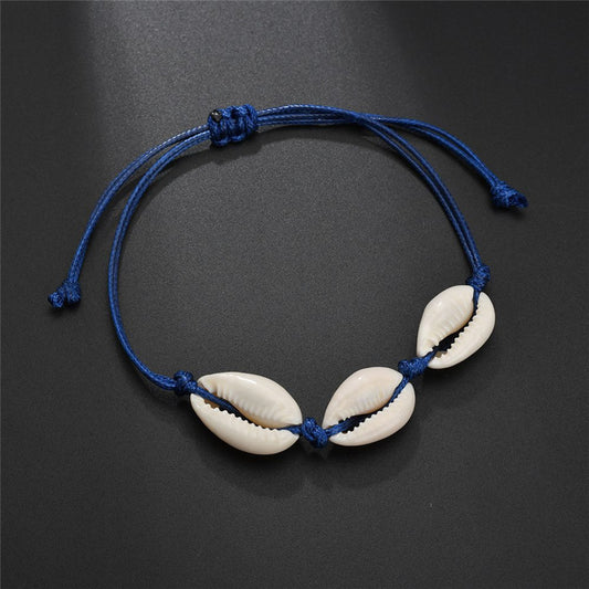 Bracelet with three cowrie shells on a dark background